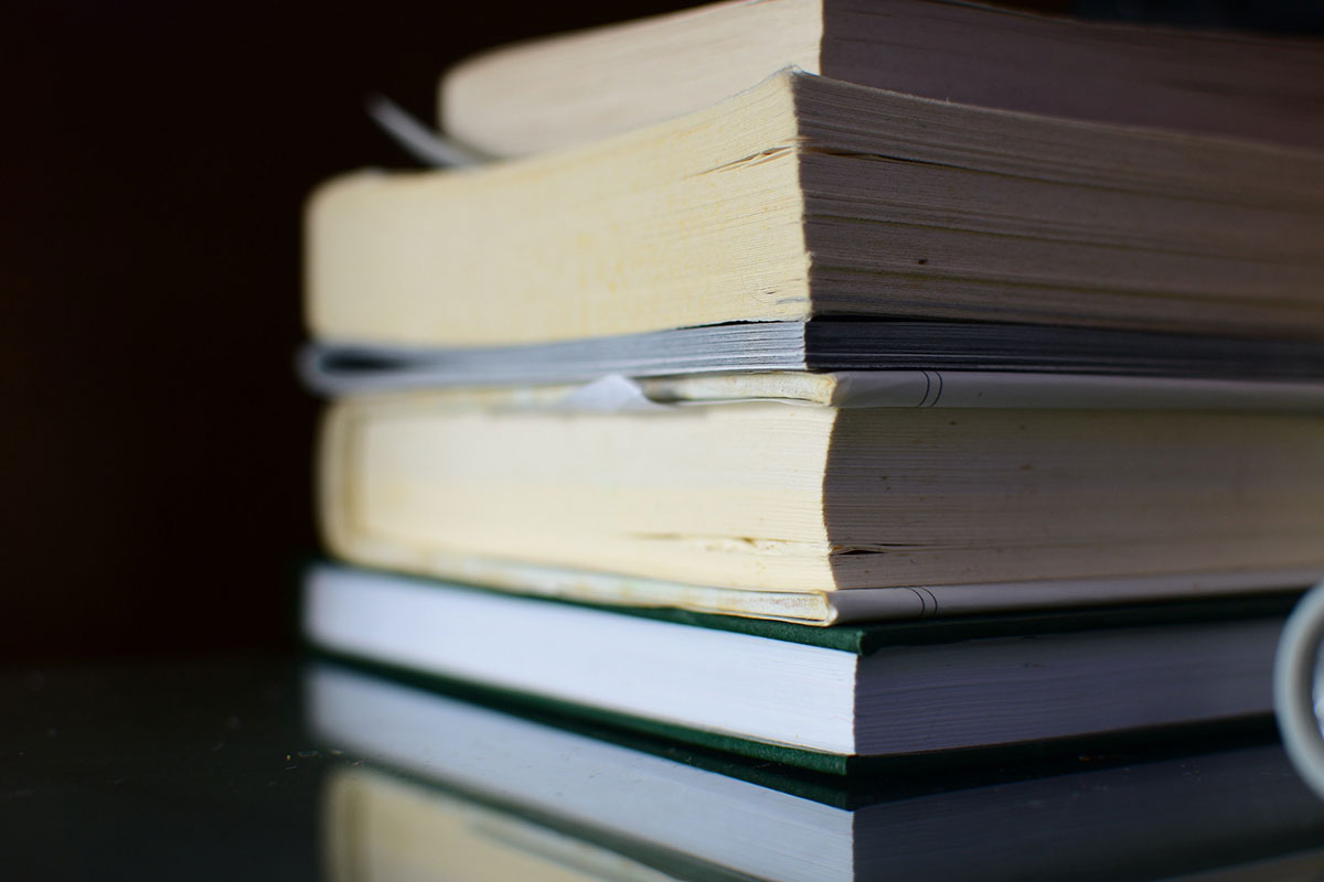 Stack of books with pages facing out in front of a dark background