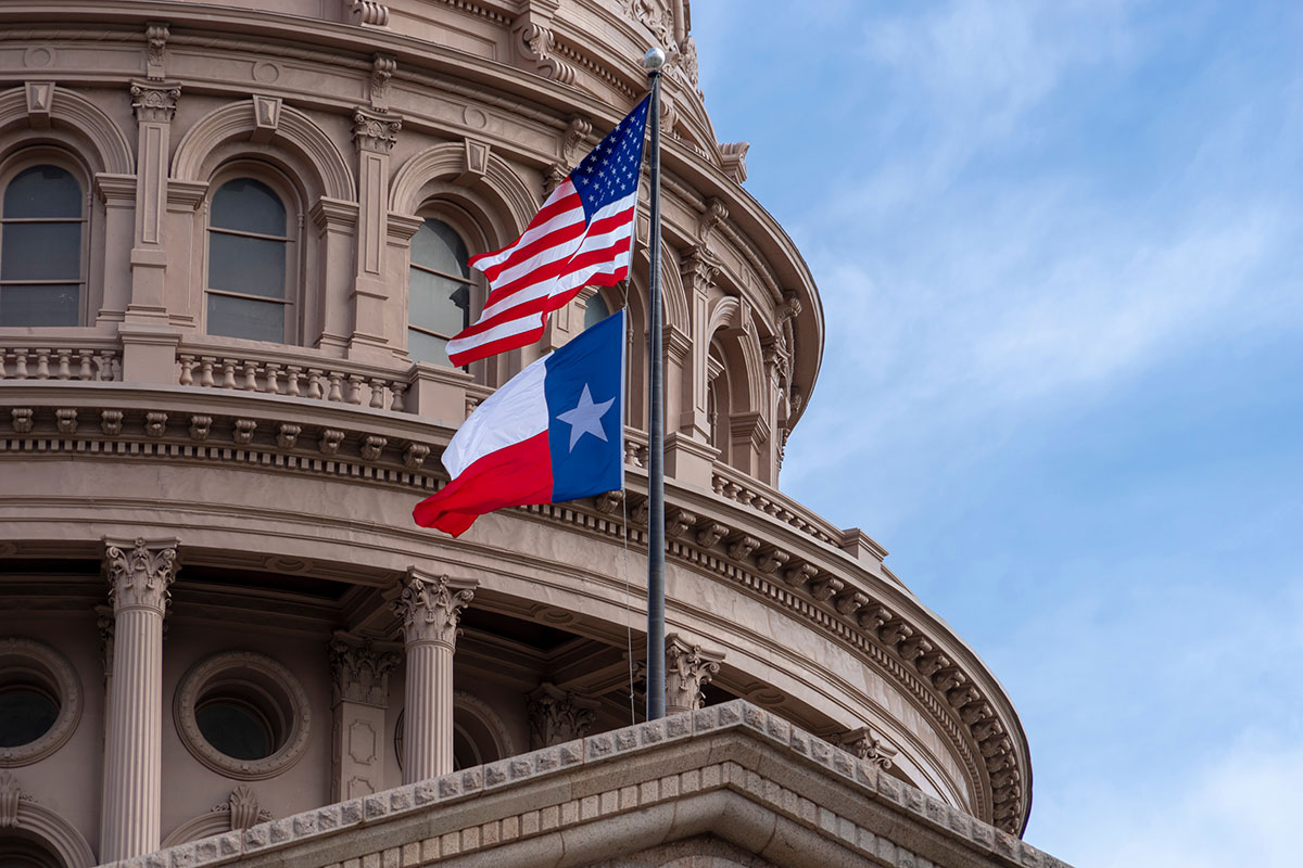 U.S. and Texas flags on Texas State Capitol in Austin, Texas