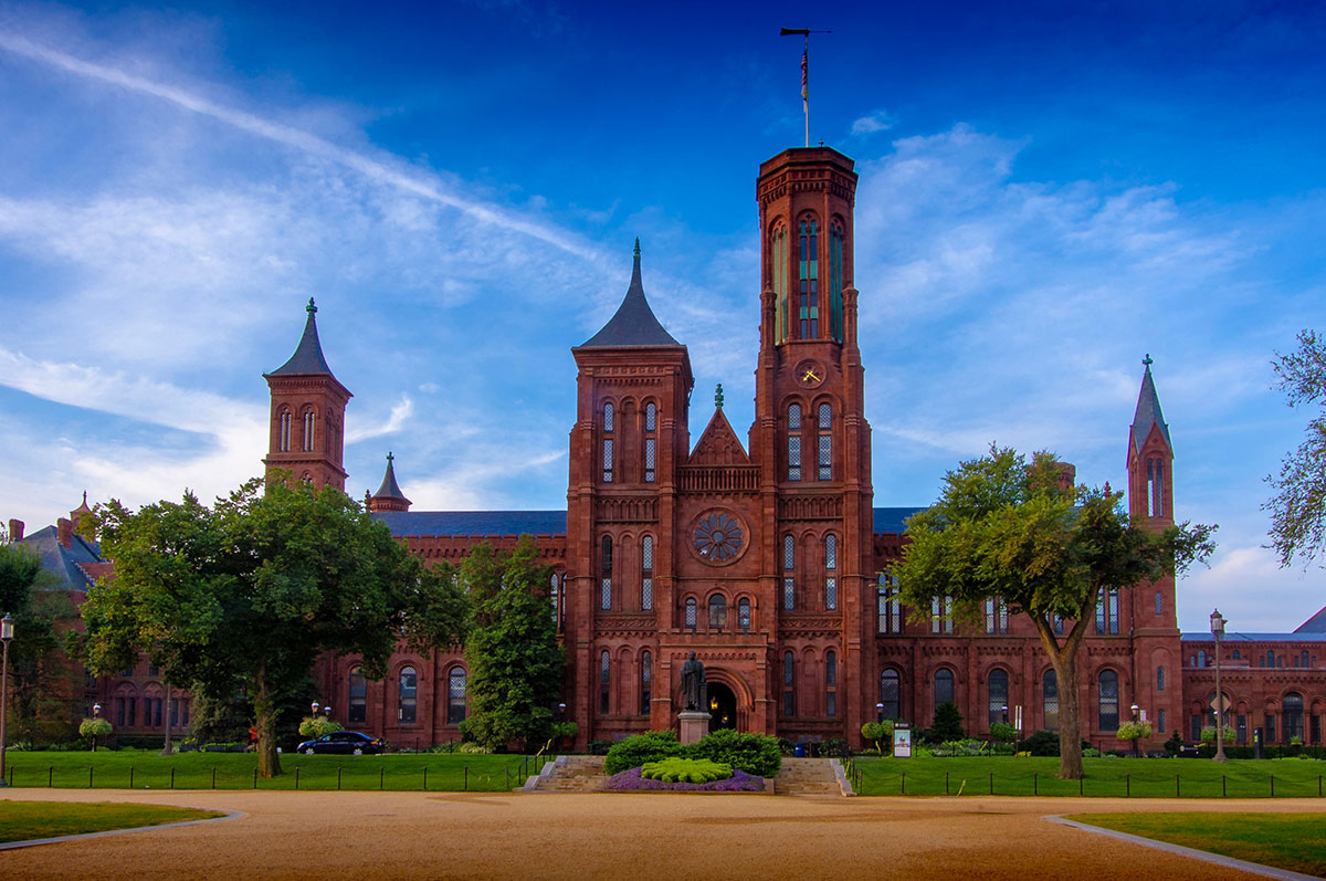 Front entrance view of the red brick Smithsonian Institution Building on the National Mall with ornate gardens and statues in front