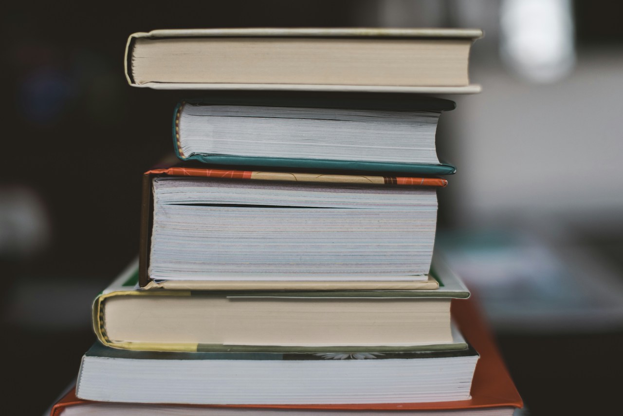 A stack of books varying in size with a blurred background.
