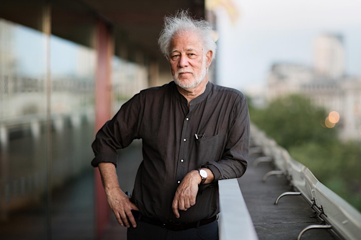 Portrait of Michael Ondaatje wearing a black button down shirt and leaning on a metal railing