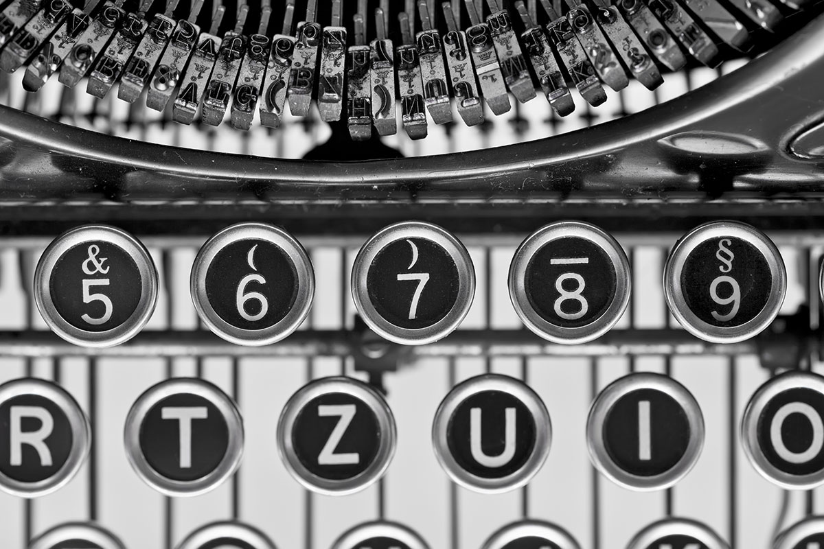 Black and white closeup of a vintage typewriter, with focus on the top two rows of the keyboard