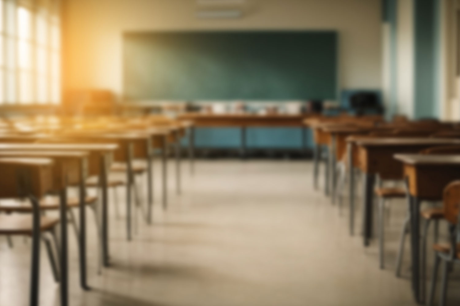 Artistically blurred empty classroom with wooden desks and green chalkboard
