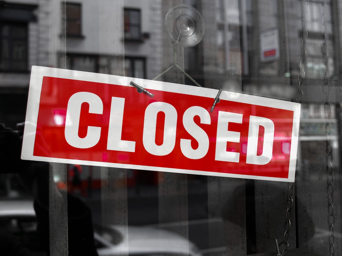 Red sign with CLOSED in big white letters in a shop window