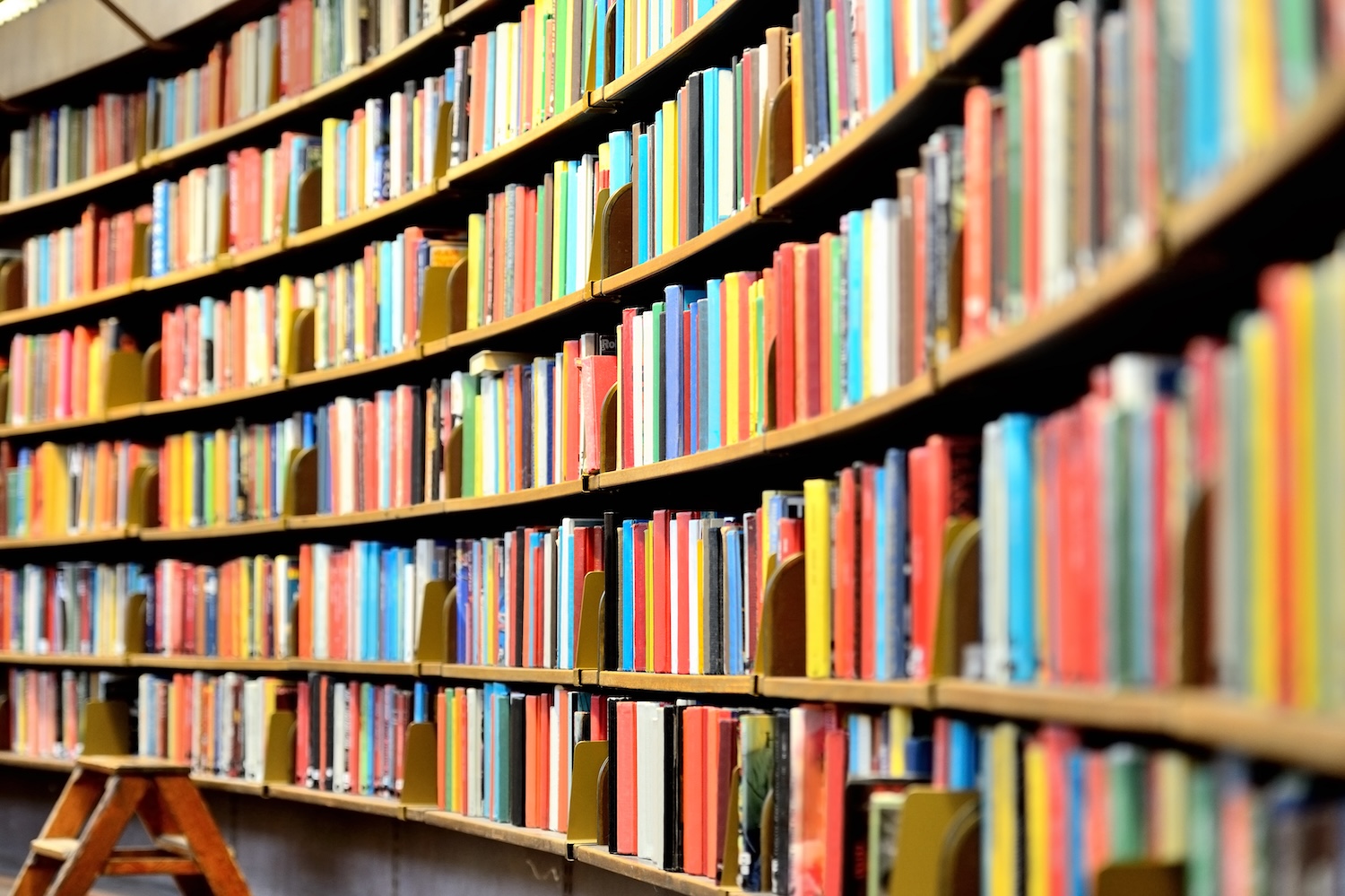 Row of curved shelves in a public library filled with brightly colored books