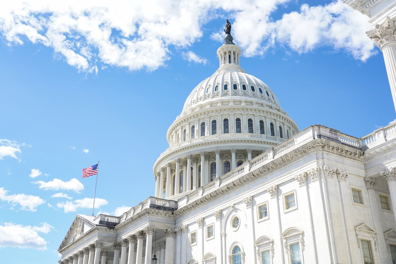 Exterior of the U.S. Capitol Building highlighted against a bright blue sky