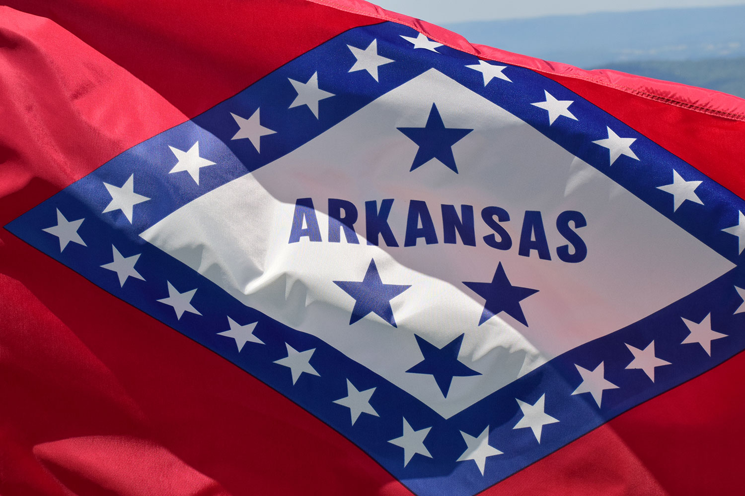 Arkansas state flag, featuring a white diamond with blue stars and a blue border on a red field